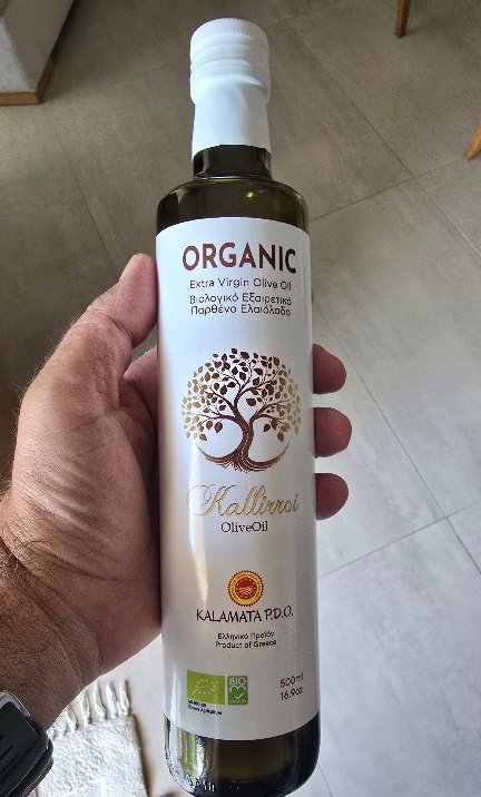 holding a white bottle of organic kallirroi olive oil kalamata PDO. premium quality of kalamata pdo